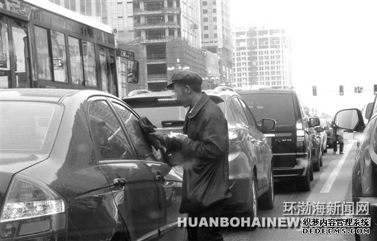 在建設(shè)路新華道路口“擦車”的行乞者。田菲菲攝